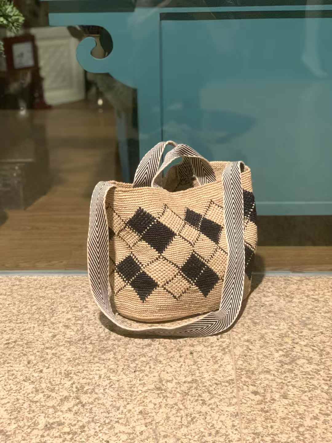 Raffia Straw Bag in classic tote shape, black diamond pattern, wide opening, Features wide, black-and-white striped handles and long cotton strap for easy crossbody or shoulder wear