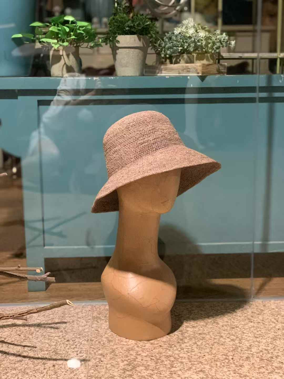 a brown color straw hat on a wooden model, minimalist style handmade in tight tension with raffia straw