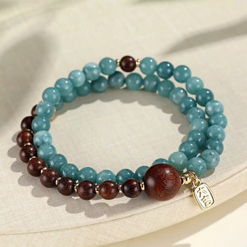 a blue color gemstone beads and wooden beads bracelet, with mini golden beads in the middle of each wooden beads. it’s designs in a ancient tradition Chinese style