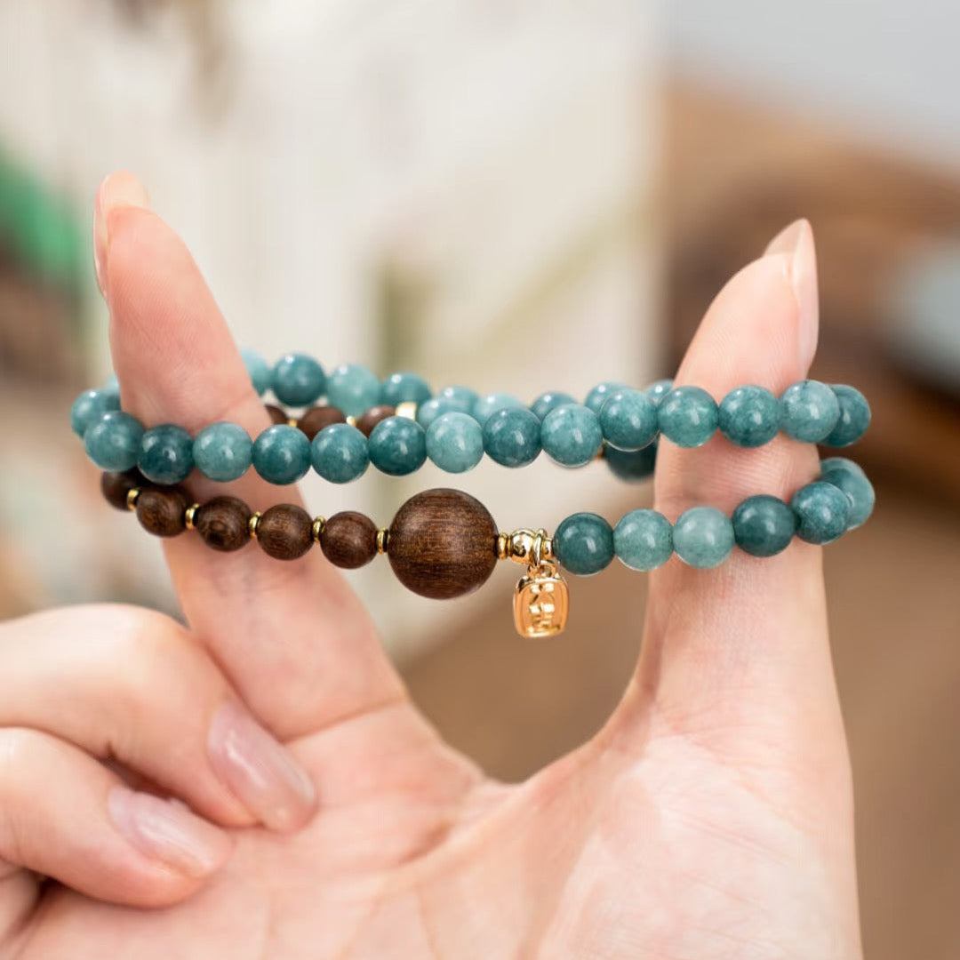 a hand wearing a calming bracelet in blue gemstone and sandalwood beads, it is a double wrap design beaded bracelet inspired by Traditional Chinese art.